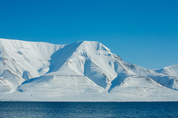 The waves of the Arctic Ocean and the snow-capped mountains of the Spitsbergen archipelago.
