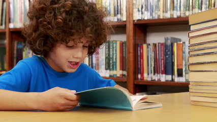 Smiling little boy reading a book - Powered by Adobe