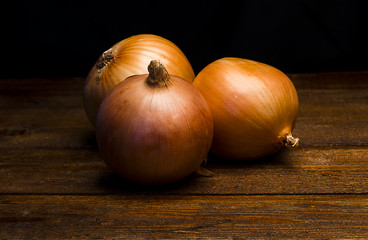 Three onions on a wooden table