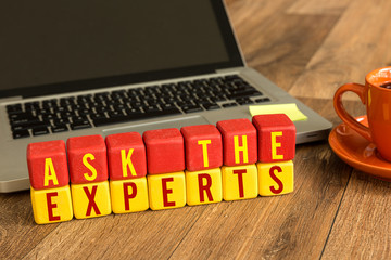 Ask the Experts written on a wooden cube in a office desk