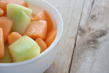 closeup melon slice in white dish with wood table background