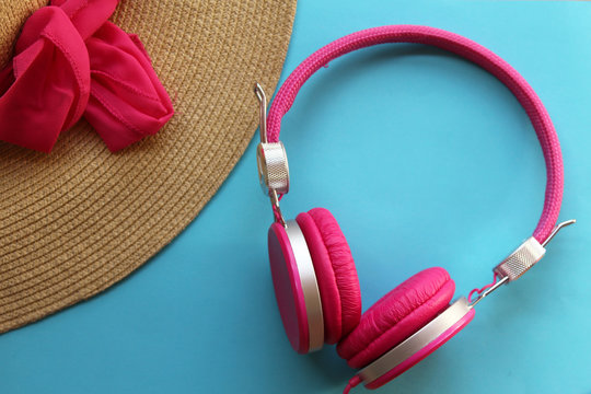Pretty straw hat and pink headphones on colorful background