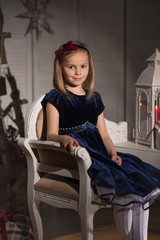 A young girl wearing a blue velvet dress.