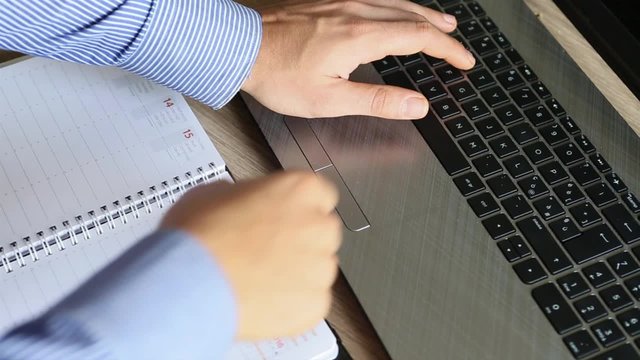 mani di uomo in ufficio che scrive email su notebook e prente appuntamento scrivendo su agenda