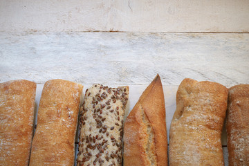 Assortment of baked bread on a white wood table. Copy space for editor's text. Top view