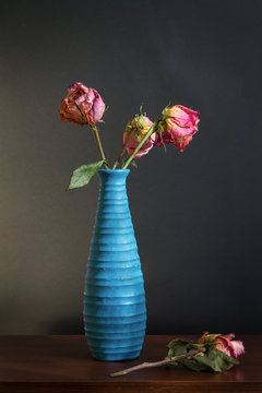 Rosas marchitas en florero azul