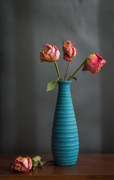 Rosas marchitas en florero azul
