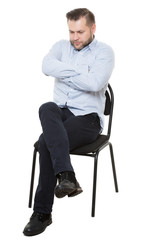 man sitting on chair. Isolated white background. Body language. gesture. Training managers. sales agents.  fully closed position. lowered eyes, drawn-neck, arms and legs crossed