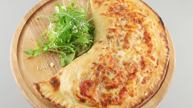 Calzone, stuffed Italian pizza on wooden board