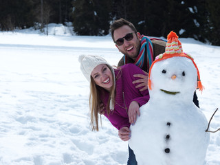 portrait of happy young couple with snowman