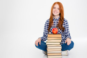 Woman sitting near stack of books with apple on top