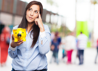 pensive young woman with piggy bank