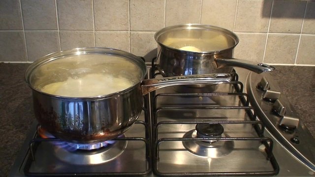 Pan of potatoes cooking on stainless steel hob