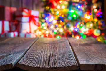 Christmas background with old wooden table, light bokeh and presents.