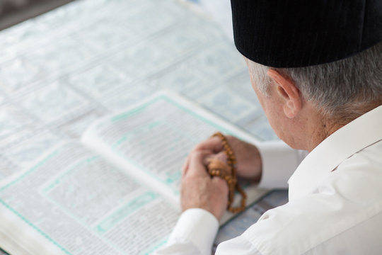 An old man reading Koran. Selective focus