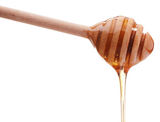 Honey dripping from a wooden honey dipper isolated on white back