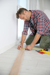 Cheerful man at home installing new wooden floor
