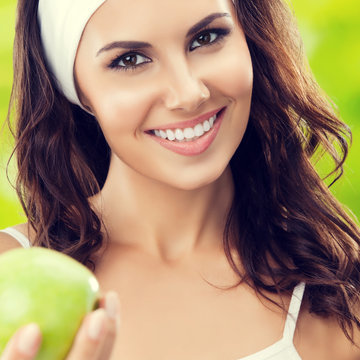 young smiling woman in sportswear with green apple, outdoor