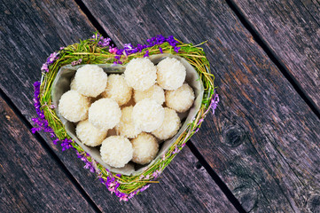 Heart shaped box filled with small candy balls for Valentine's Day. White coconut candy