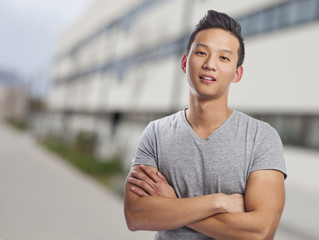 portrait of young asian man standing in front of university