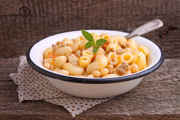 pasta with meat and beans in a white bowl on the old wooden background