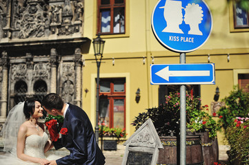 Fototapeta na wymiar Wedding couple on streets of old city kissing on kiss place plat