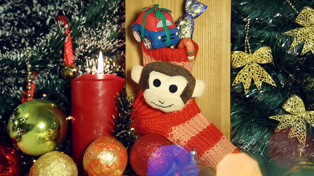 Red candle lights and red christmas sock with monkey next year symbol like a christmas background. Hand puts a gift - candy in Christmas socks.