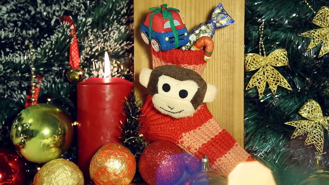 Red candle lights and red christmas sock with monkey next year symbol like a christmas background. Hand puts a gift - candy in Christmas socks.