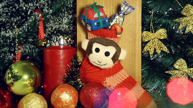 Red candle lights and red christmas sock with monkey next year symbol like a christmas background. The candle inflames.