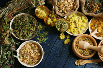 Naklejka premium Assortment of dry medicinal herbs in bowls on wooden background top view