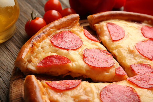Hot tasty pizza with salami on wooden background, close up