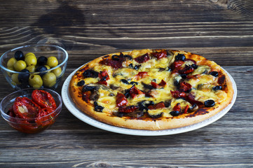 Delicious fresh pizza and sun-dried tomatoes served on wooden table