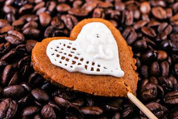 Gingerbread heart on coffee beans background close up. Shallow dof