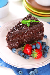 Fototapeta na wymiar Chocolate cake with chocolate cream and fresh berries on plate, on wooden background
