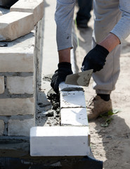 Builder lays bricks in cement mortar