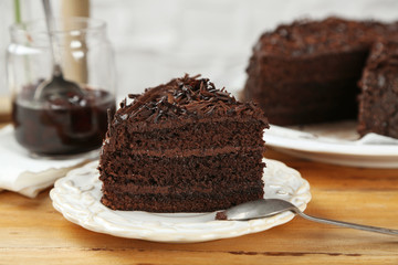 Fototapeta na wymiar Sliced chocolate cake on wooden table, on light background