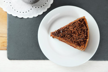 Sliced chocolate cake on wooden table, on light background