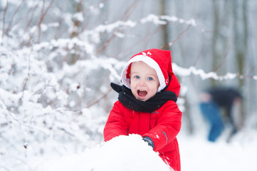 The kid builds a snowman from snow.