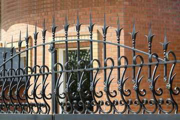 Forged fence of gate against a  brick wall