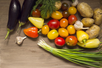 Garlic bulbs and vegetables still life, potato, green onion, pepper, tomatoes and eggplant on wooden table. Top view.