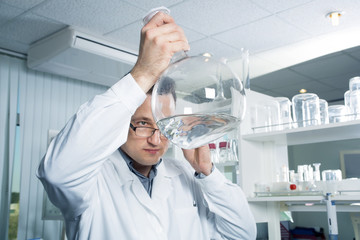 Laboratory assistant looking in a bottle with liquid