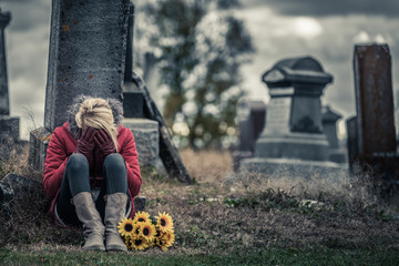 Lonely Sad Young Woman in Mourning in front of a Gravestone