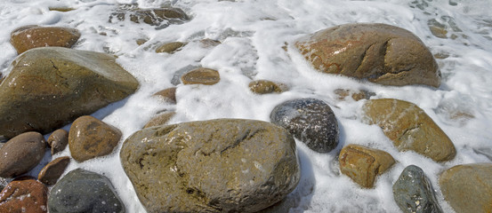 Slow waves on a rocky beach in summer
