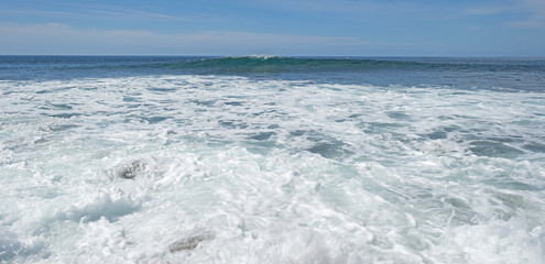 Naklejka na ściany i meble Slow waves on a rocky beach in summer