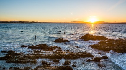 Obraz premium Surfer on waves in the sunset at byron bay