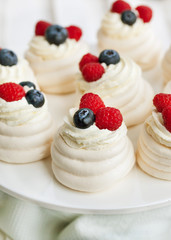 Pavlova meringue cakes decorated with fresh berries
