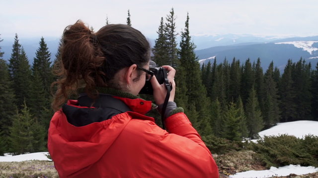 female hiker taking shots of a landscape in mountains