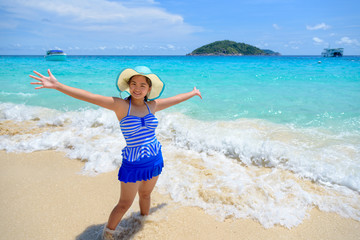 Fototapeta na wymiar Beautiful woman in a swimwear striped blue hat standing with arms outstretched to life carefree at sea and sky in summer on the beach of Miang Island, Mu Ko Similan National Park, Phang Nga, Thailand