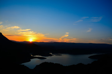 Fototapeta premium lake and hills under a colorful sky at sunset