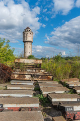 Abandoned water tower near old railway track with obsolete railway parts